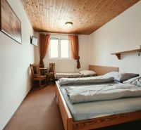 Schlafzimmer im Ferienapartment mit zwei Betten und Fernseher, Boden mit Holzdekor.