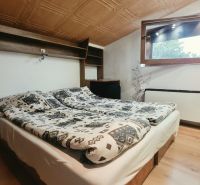 Dachgeschoss-Schlafzimmer mit Doppelbett, Regal und Fenster, Ferienwohnung.