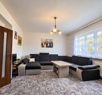 Wohnzimmer in einem Einfamilienhaus mit großem Sofa und auffälligem Teppich.