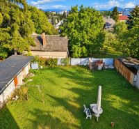 Der Garten eines Einfamilienhauses in Martin mit Rasen und sichtbaren Dächern der nahegelegenen Gebäude.
