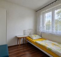 Einzelzimmer mit Bett und Tisch, Boden mit Holzdekor, weißes Interieur.