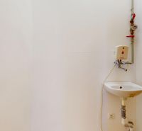 Weiße Wand mit Waschbecken und Wasserhahn in Geschäftsräumen.