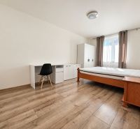Ein Zimmer in einer 2-Zimmer-Wohnung mit einem Bett, einem Tisch und einem Boden in Holzoptik.