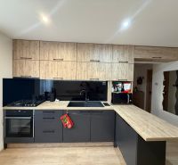 Küche in einer 2-Zimmer-Wohnung mit schwarzen Schränken und einem Boden in Holzoptik.