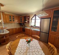 Die Küche eines Einfamilienhauses mit Holzmöbeln, einem Boden mit Holzdekor und einem Esstisch.