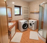 Badezimmer in einem Einfamilienhaus mit Waschmaschine, Trockner und Duschkabine.