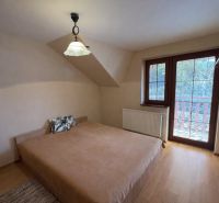 Ein Schlafzimmer in einem Einfamilienhaus mit einem Bett und einem Boden in Holzoptik.