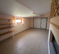 Innenraum eines Einfamilienhauses mit Fliesenboden, Stauregale und einem Fenster mit zarten Vorhängen.
