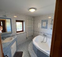 Badezimmer mit Badewanne und Waschbecken in einem Einfamilienhaus, geflieste Wände.