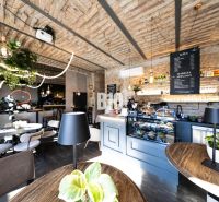Stilvolle Gastronomiebereiche mit Backsteingewölben, Grünpflanzen und einem Boden in Holzoptik.