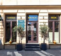 Das Äußere eines Cafés und einer Bar in Bratislava - Altstadt mit drei Eingängen und Schildern.
