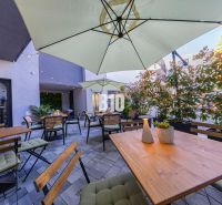 Außenbereiche der Gastronomie in Bratislava - Altstadt mit Holztischen und Sonnenschirmen.