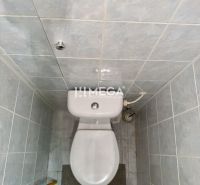 Toilette mit blauen Fliesen in einer 2-Zimmer-Wohnung, einfaches Interieur.
