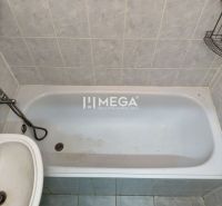 Badezimmer mit Badewanne und Waschbecken in einer 2-Zimmer-Wohnung, gefliest mit hellen Fliesen.