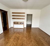 Ein Zimmer in einer 3-Zimmer-Wohnung mit einem Boden in Holzoptik und Regalen an der Wand.