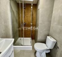 Badezimmer in einer Einzimmerwohnung mit Duschkabine und Keramikfliesen.