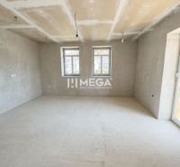 Ein geräumiges Zimmer in einem Einfamilienhaus mit großen Fenstern und Betonboden.