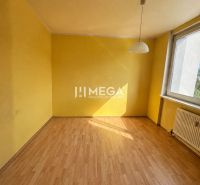 Gelbes Zimmer mit großem Fenster und Holzboden in einer 3-Zimmer-Wohnung.