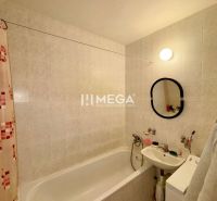Badezimmer mit Badewanne und Waschbecken in einer 3-Zimmer-Wohnung, helle Fliesen.