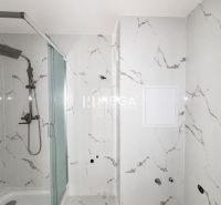 Badezimmer mit Duschkabine in einer 2-Zimmer-Wohnung mit Marmorfliesen.