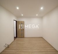 Ein leerer Raum in einer Ferienwohnung mit Holzboden und heller Wandfarbe.