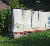 Ein älteres Lagerhaus im Garten der Straße in Humenné, umgeben von Grün und wachsendem Gras.