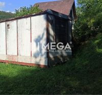 Ein Häuschen mit schrägem Dach, umgeben von Grün in den Gärten in Humenné.