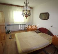 Schlafzimmer im Einfamilienhaus mit Kronleuchter, Bett und Boden mit Holzdekor.