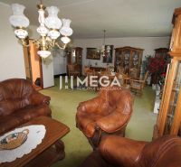 Wohnzimmer in einem Einfamilienhaus mit Ledersofa, Holzmöbeln und einem verzierten Kronleuchter.