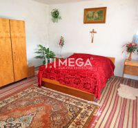 Ein Schlafzimmer in einem Einfamilienhaus mit einer roten Decke, Holzmöbeln und dekorativen Blumen.