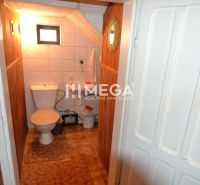 Toilette mit Fliesen und kleinem Fenster in einem Einfamilienhaus.