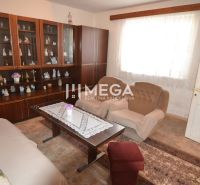 Wohnzimmer in einem Einfamilienhaus mit Vitrine, Sesseln und Tisch mit Spitze.