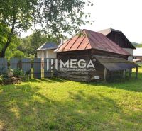 Ein Holzhaus im Dorf Vyšné Ladičkovce, umgeben von Grün und einem Zaun.