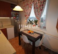 Küche in einer 3-Zimmer-Wohnung mit Tisch, Blumenvorhängen und Holzboden.