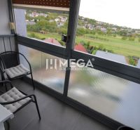 Ein verglaster Balkon mit Blick auf Grünflächen und das Dorf, aus einer 3-Zimmer-Wohnung.