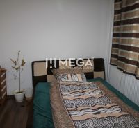 Schlafzimmer in einer 3-Zimmer-Wohnung mit Bett, Holzboden und gestreiften Vorhängen.