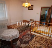 Ein Zimmer mit Betten und einem Kinderbett in einem Einfamilienhaus, dekoriert mit Vorhängen und Teppichen.
