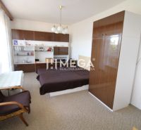 Schlafzimmer in einem Einfamilienhaus mit Bett, Schränken und Sessel, Dekorationen auf den Regalen.