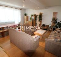 Wohnzimmer in einem Einfamilienhaus mit Holzboden, Sofa und Blumen.