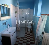 Ein Badezimmer in einem Einfamilienhaus mit blauen Fliesen, einer Dusche und einem Waschbecken.