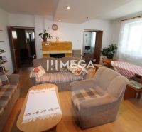 Wohnzimmer in einem Einfamilienhaus mit Sofas, Tisch und Kamin, auf einem Boden mit Holzdekor.