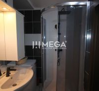 Badezimmer in der Ferienwohnung mit Waschbecken, Duschkabine und beleuchtetem Spiegel.