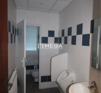 Bürotoilette mit weißen und blauen Fliesen, Waschbecken und Urinal.