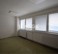 Ein leeres Büro mit einem Heizkörper und Jalousien an den Fenstern, ein Boden ohne Holzdekor.