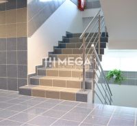 Eine Treppe mit grauen Fliesen und einem Metallgeländer in einem Bürogebäude.