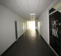 Ein langer Flur im Büro mit dunklem Boden und weißer Decke.