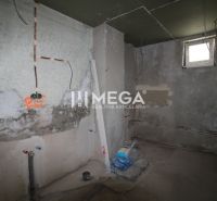 Nedokončená miestnosť v rodinnom dome s nedokončenými stenami a stavebným materiálom.