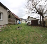 Der Garten bei einem Einfamilienhaus in der Straße in Pakostov, mit einem älteren Holzschuppen und Rasen.
