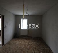 Eckzimmer in einem Einfamilienhaus mit Betonboden und nackten Wänden.