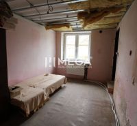 Unmöbliertes Interieur eines Einfamilienhauses mit Bett und freiliegender Decke.